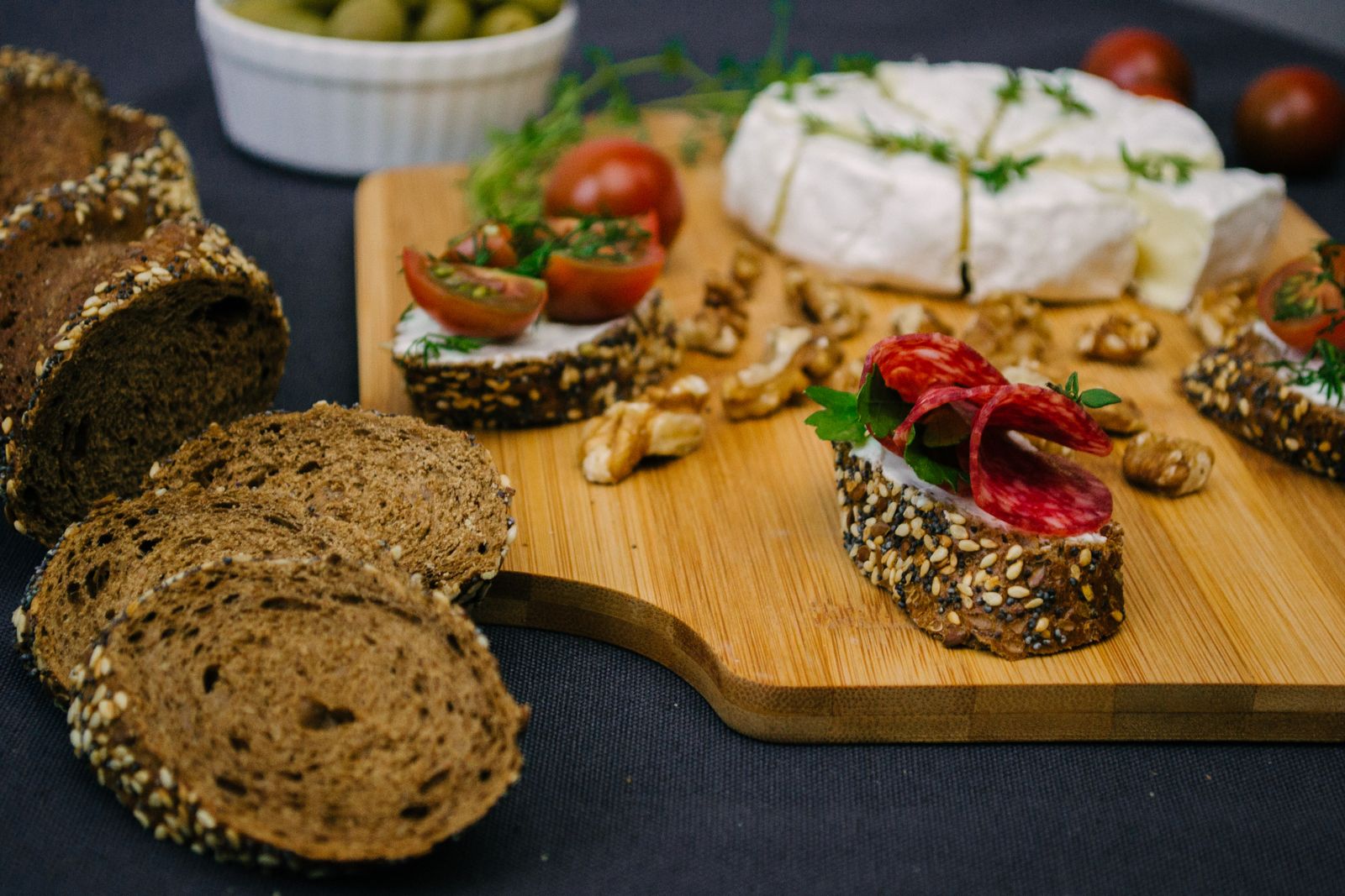 Brotzeitbrett mit Körnerbrot, Camembert, Salami, Tomaten und Walnüssen